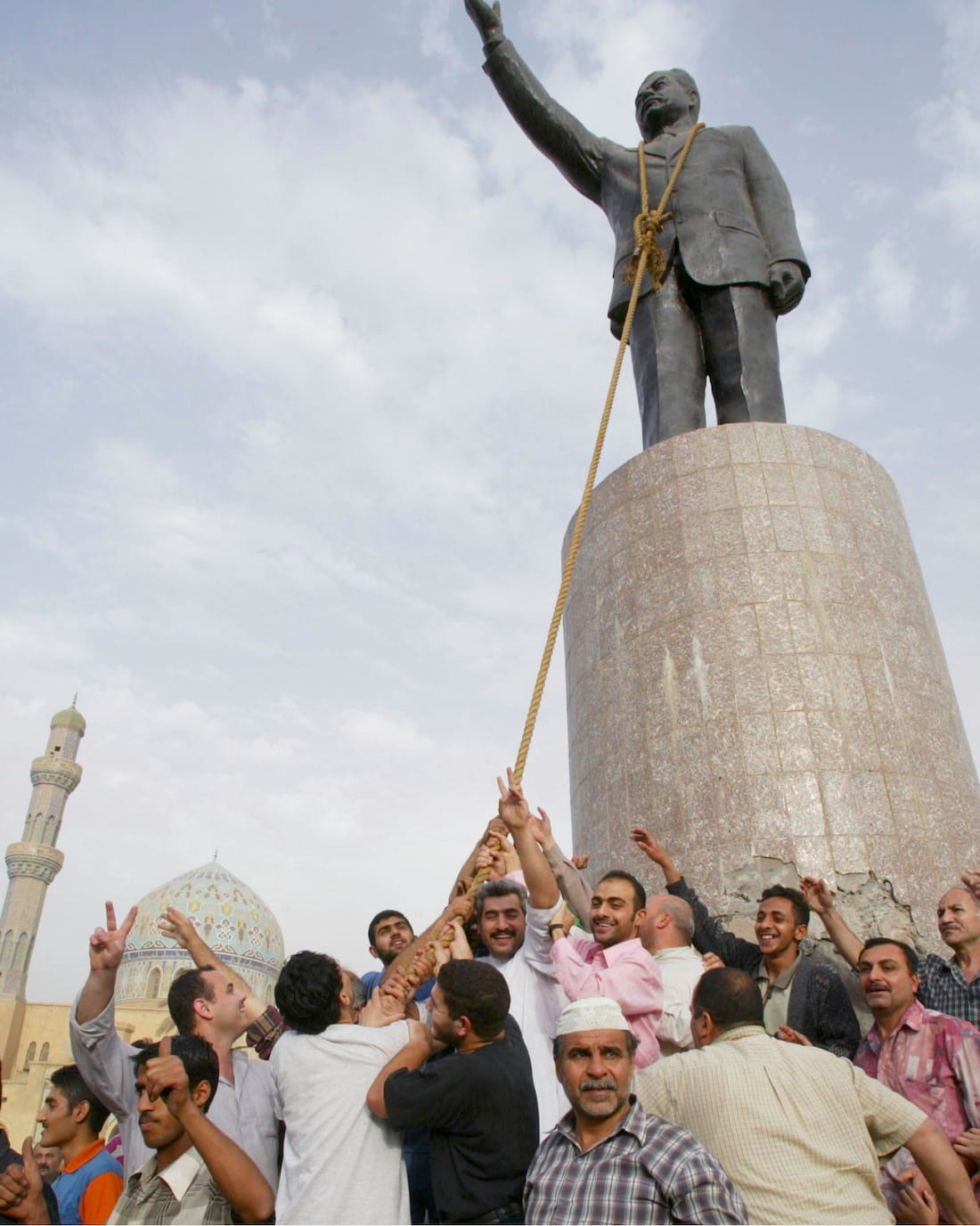 People pulling down a statue of Saddam Hussein.