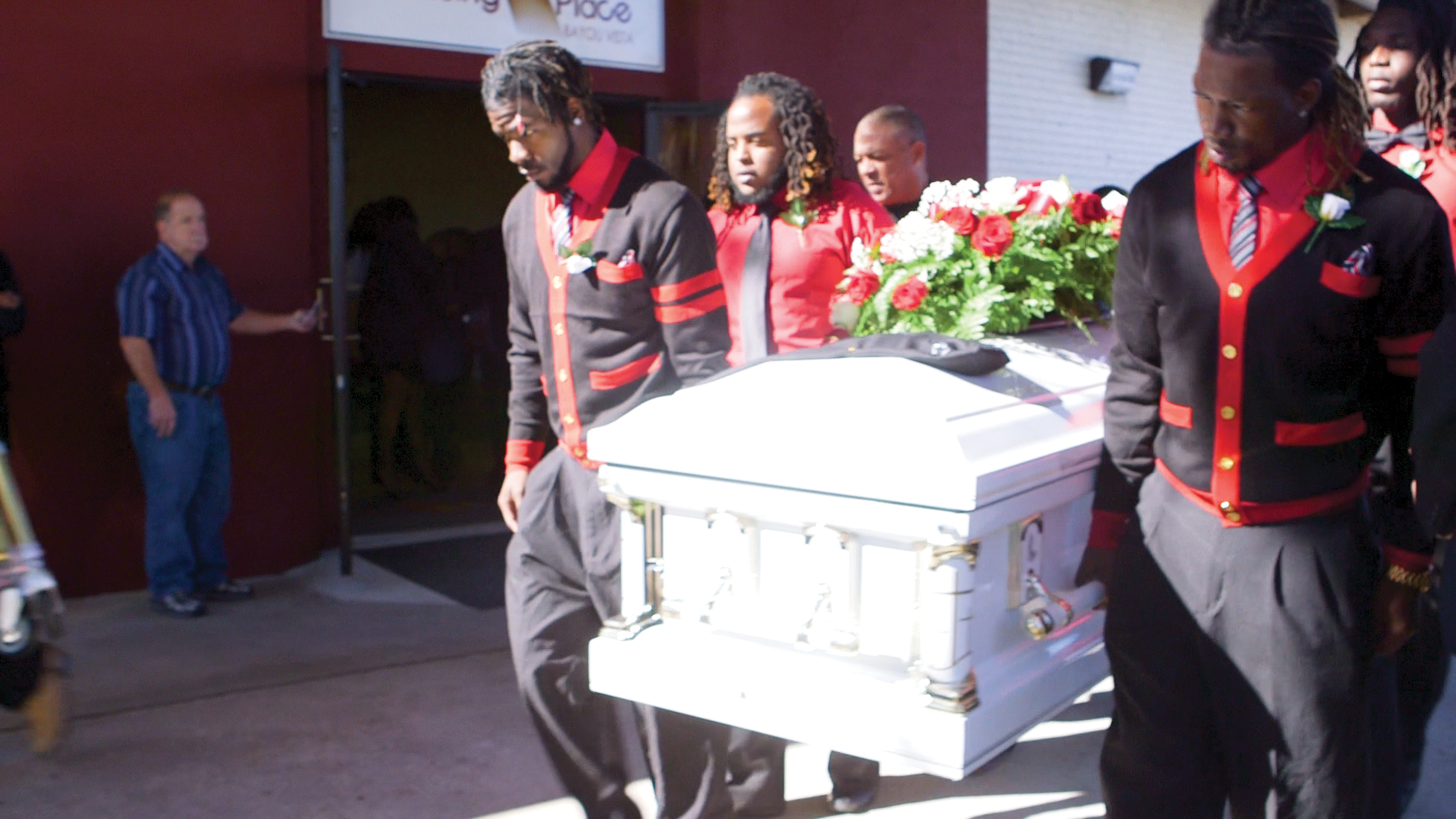 Afroamerikanische Männer tragen einen weißen Sarg