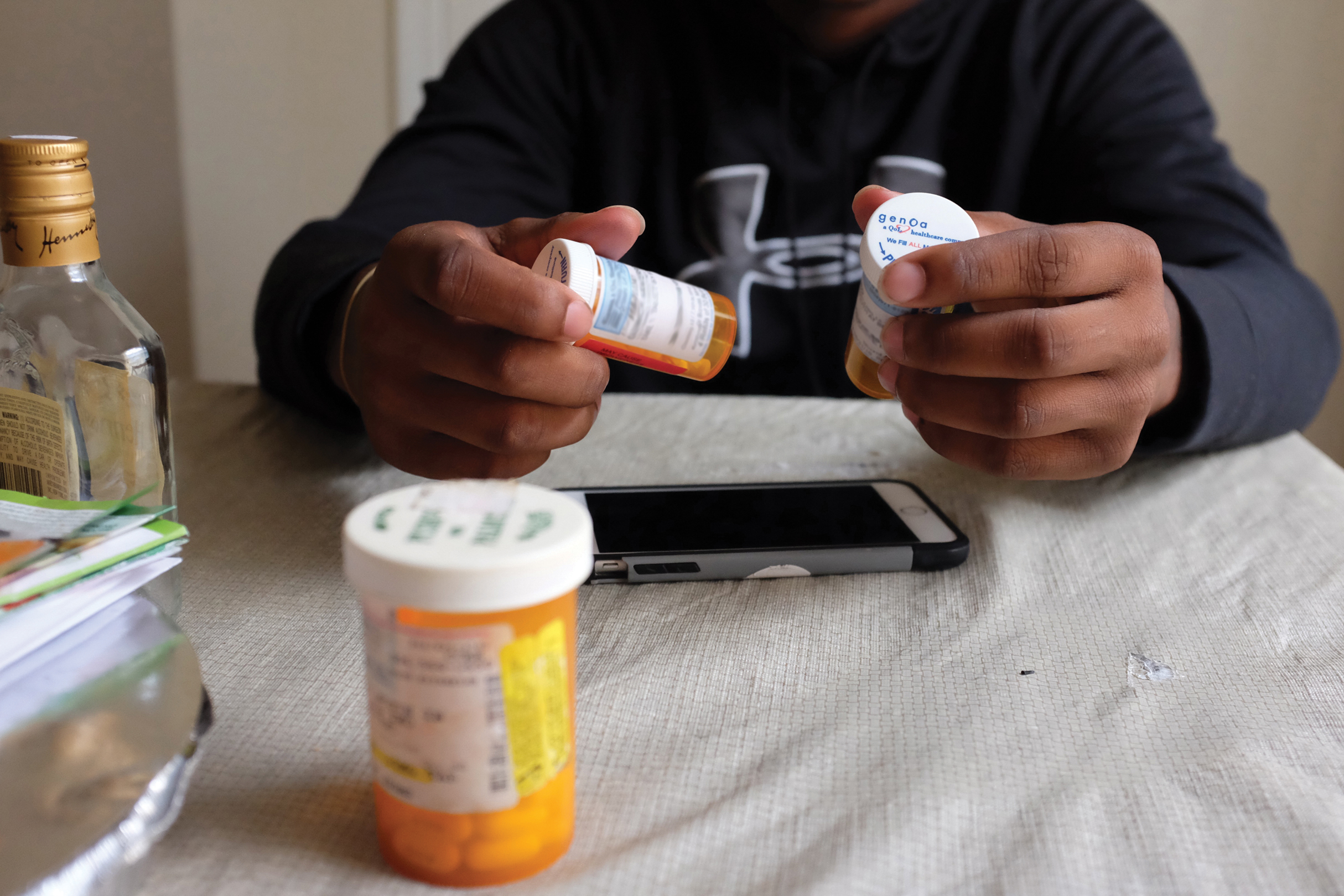 Hände in Nahaufname, die verschiedene Dosen mit verschreibungspflichtigen Medikamenten halten