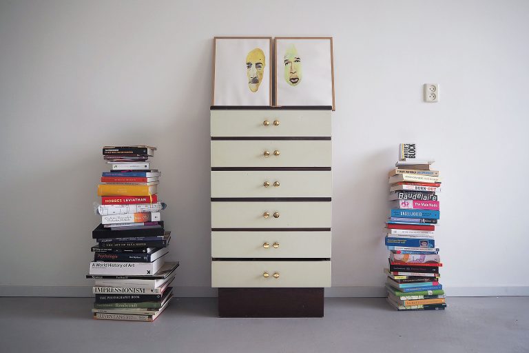 Op elkaar gestapelde boeken en kastje.