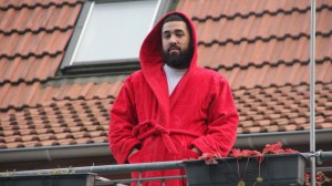Ein Mann im roten Bademantel steht auf einem Balkon