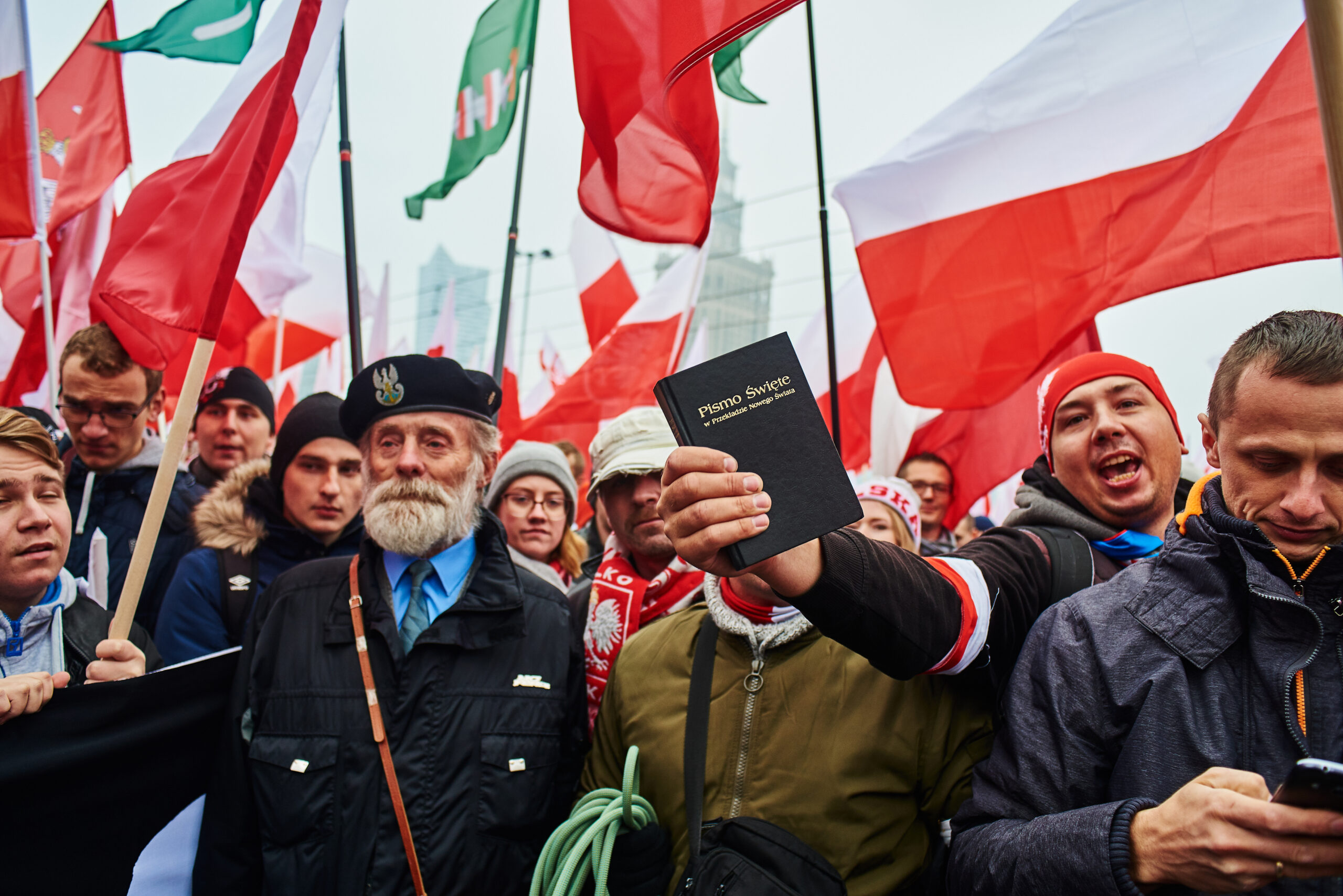 Marsz Niepodległości 2018. Mężczyzna w tłumie trzyma Biblię