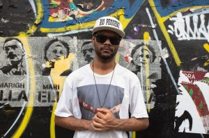 Retrato de um rapaz negro em frente a um muro com cartazes