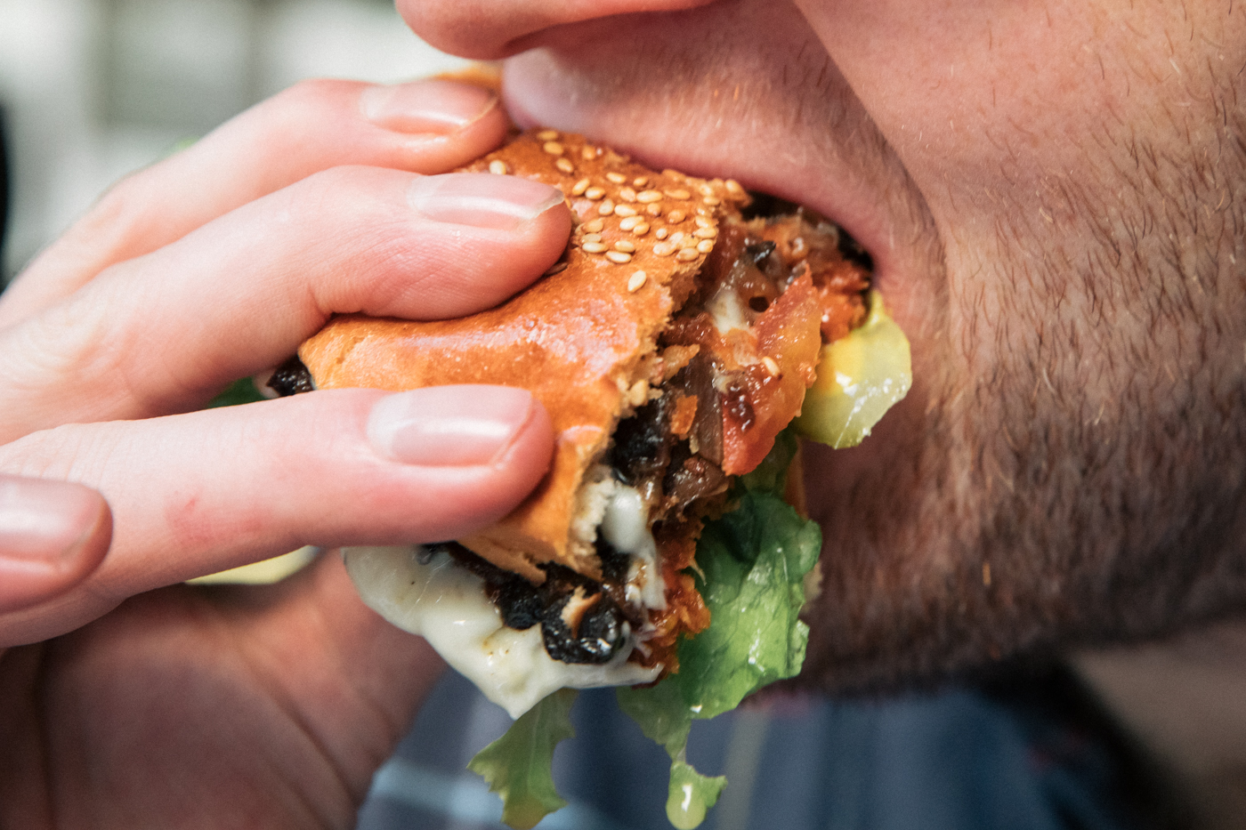 Nahaufnahme des Autors mit veganem Burger im Mund