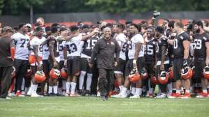 Hue Jackson walks across a field surrounded by his team.