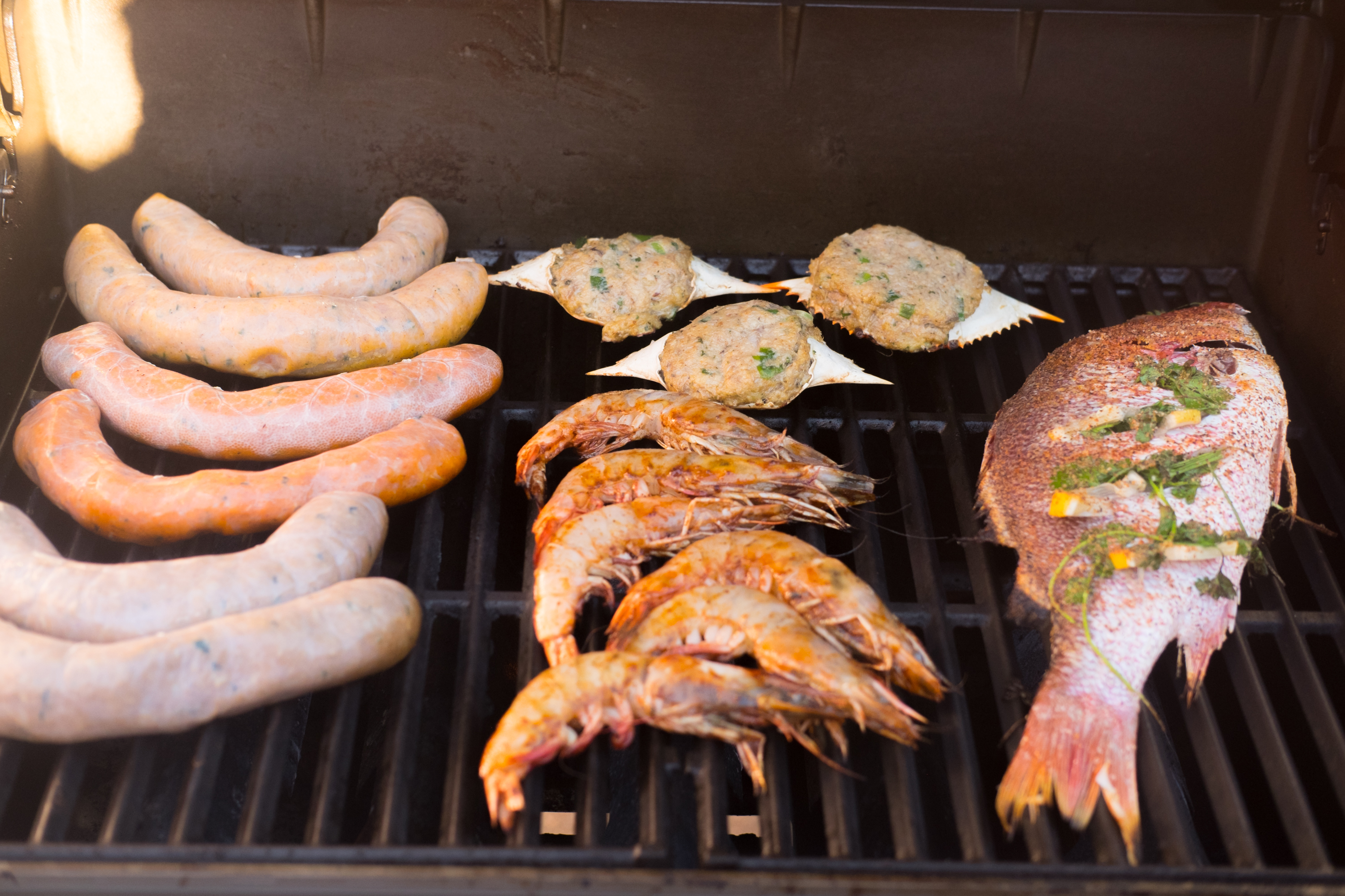 sausages, shrimp, and fish on a grill