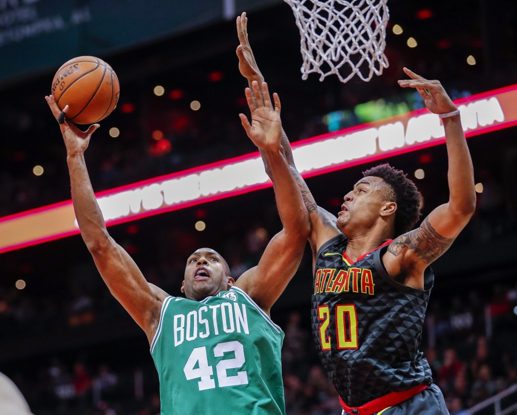 John Collins defends a shot from Al Horford.