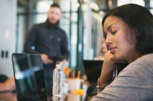 A tired woman sleeps in an open-plan office