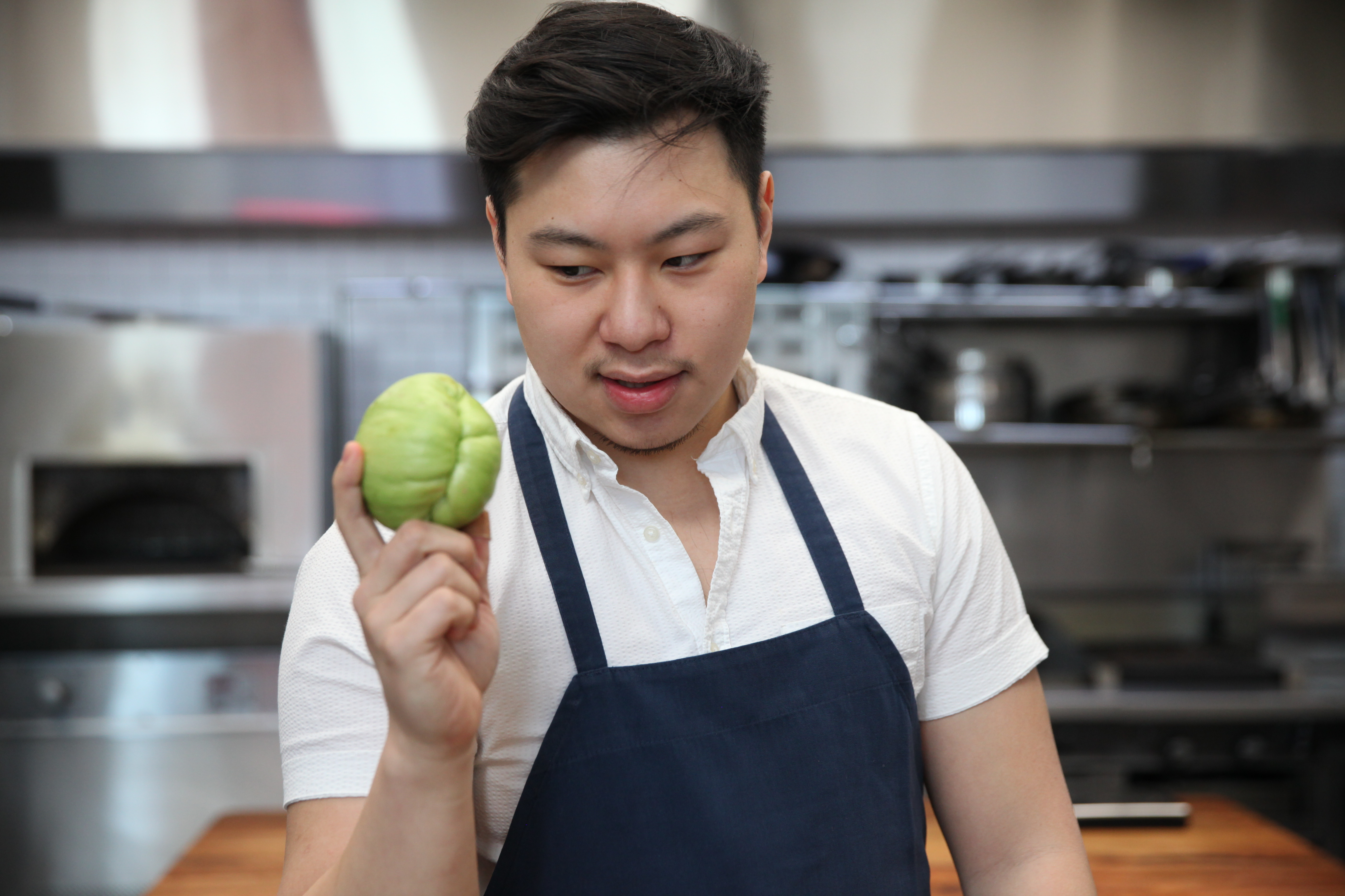 chef lucas sin of junzi kitchen holding a chayote