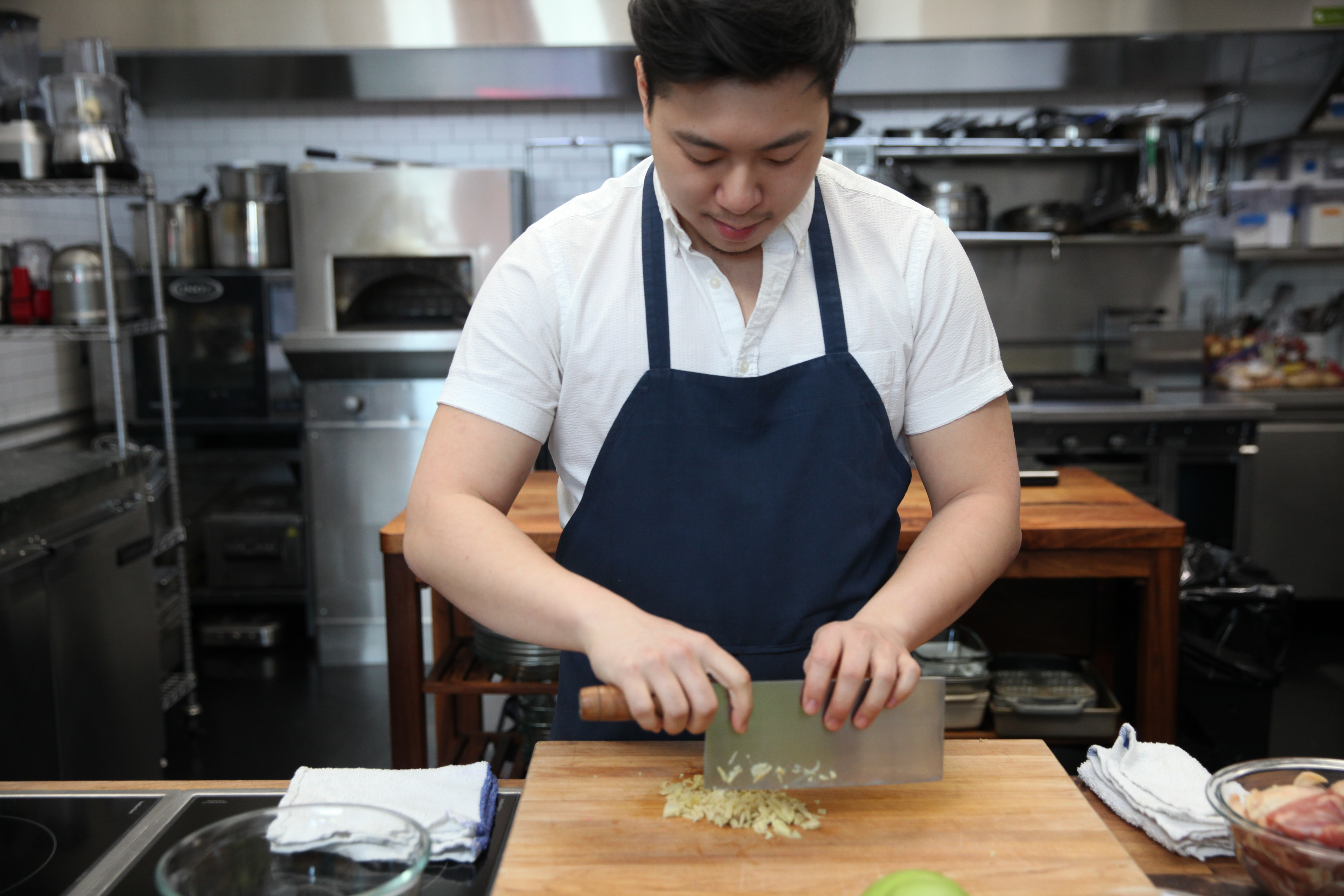 chef lucas sin of junzi kitchen chopping ginger with a cleaver