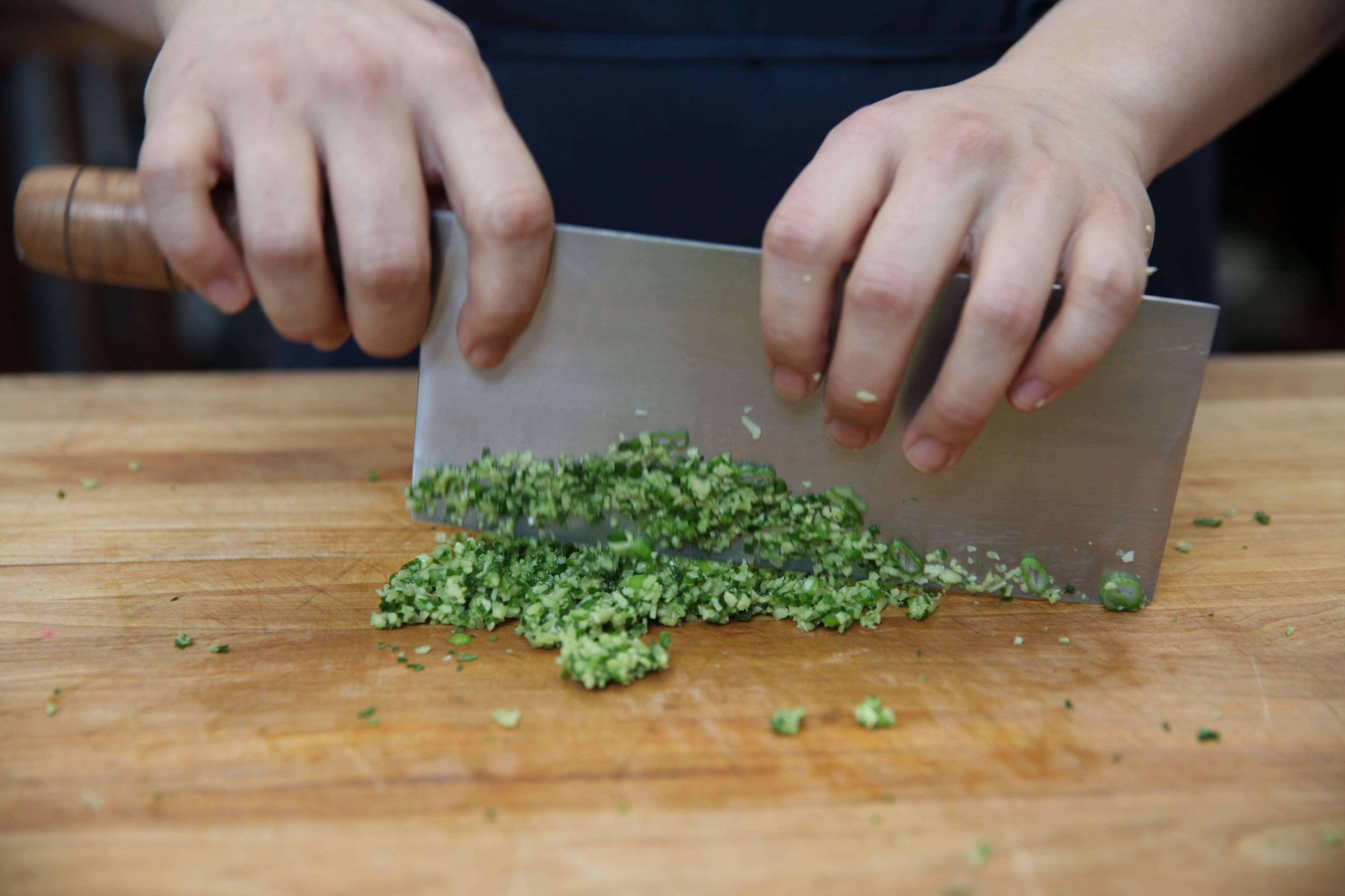chef lucas sin's hands chopping scallions and ginger for a chicken marinade