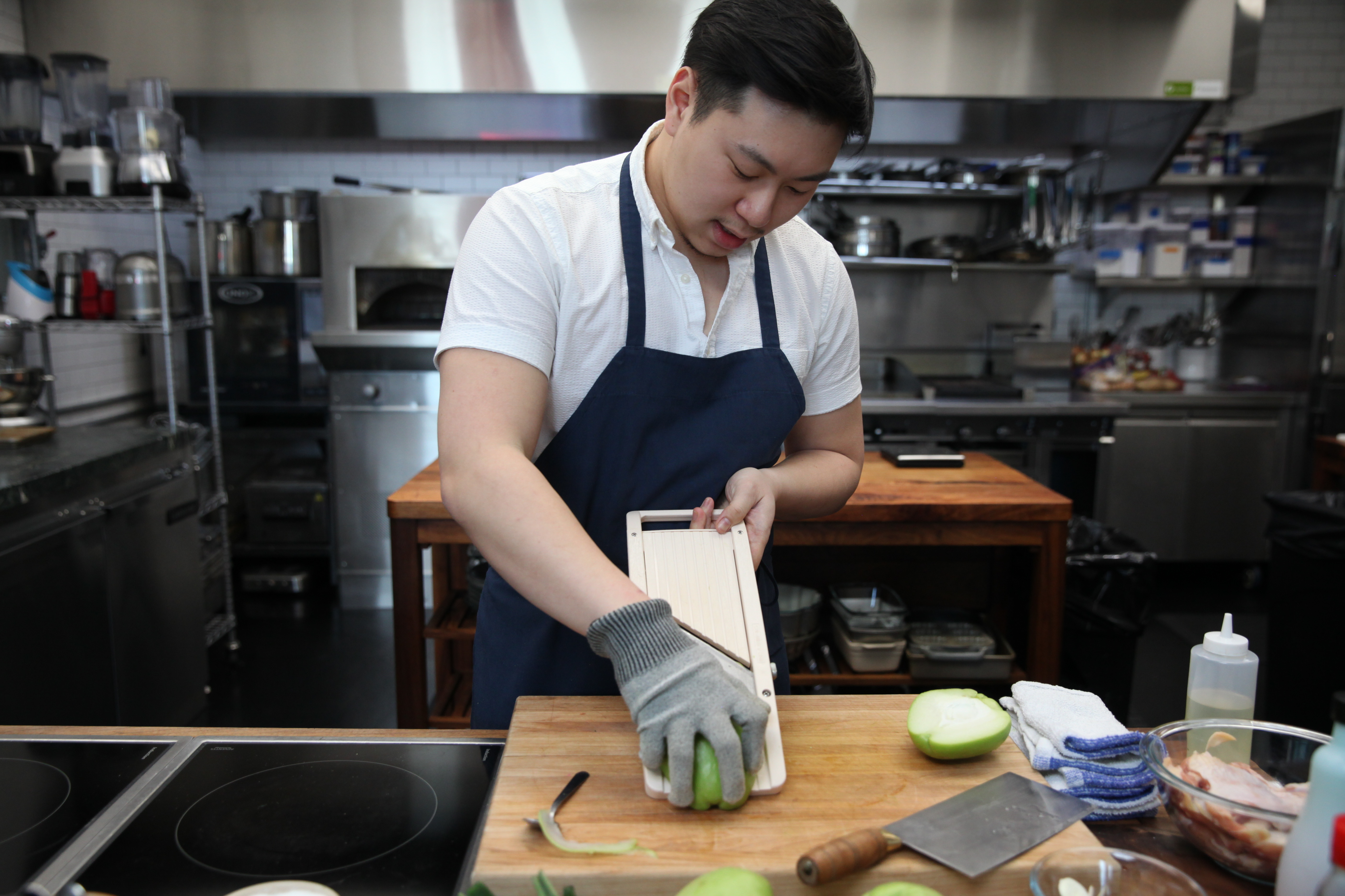 chef lucas sin of junzi kitchen cutting chayote on a mandolin