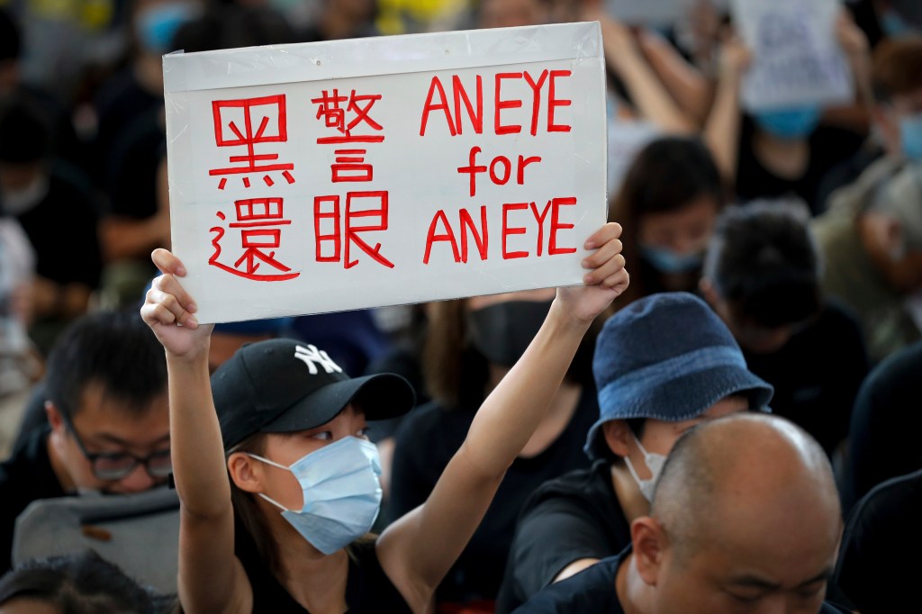 Demonstran membawa papan mengkritik polisi Hong Kong saat menduduki bandara. Foto oleh Vincent Thian/Associated Press