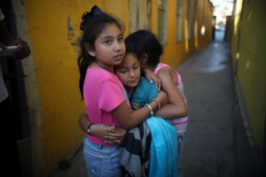 A Honduran girl, center, is hugged by friends as she leaves the Agape World Mission shelter after her family decided to abandon their asylum case and accept voluntary return to Honduras, after spending nearly six months at the border, in Tijuana, Mexico,