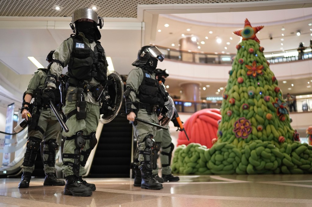 Riot police past by a Christmas decor in a mall during a protest rally on Christmas Eve in Hong Kong on Tuesday, Dec. 24, 2019.