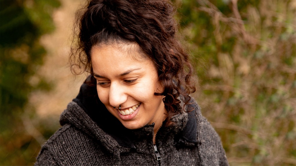 Berna, eine junge Frau mit braunen Locken und breitem Lächeln