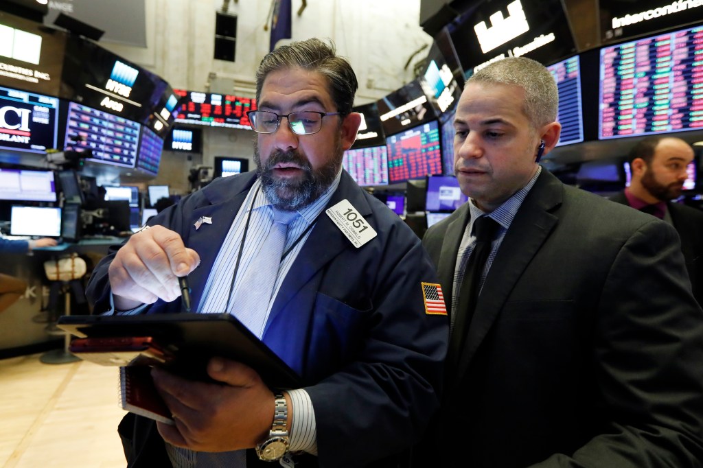 Specialist John O'Hara, center, works on the floor of the New York Stock Exchange, Wednesday, March 11, 2020. (AP Photo/Richard Drew)