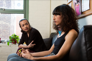 A genderqueer person and a trans woman sitting in a doctor's office.