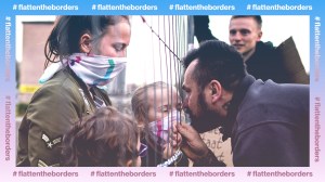 Ein Mann berührt durch einen Zaun hinweg ein Kind mit Atemschutzmaske.