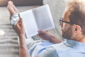 White man with glasses reading a book