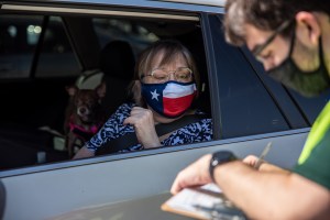 A poll worker helps a voter at a mail in ballot drop off location on October 13, 2020 in Austin, Texas.