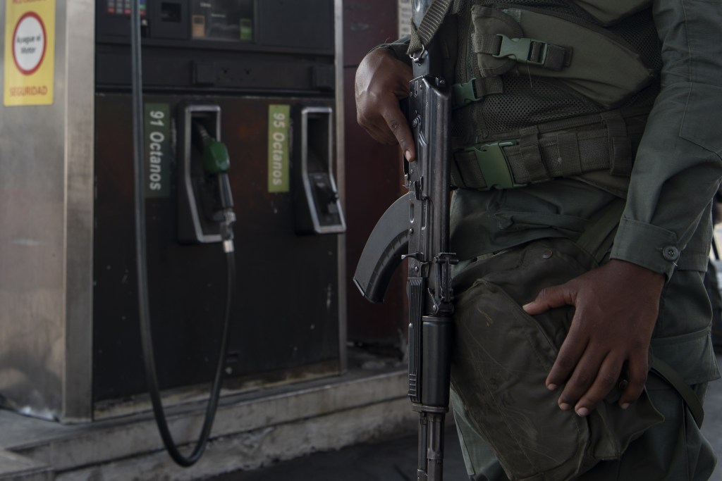 A member of the Bolivarian National Guard (GNB) holds a gun while standing guard outside a gas station in Caracas