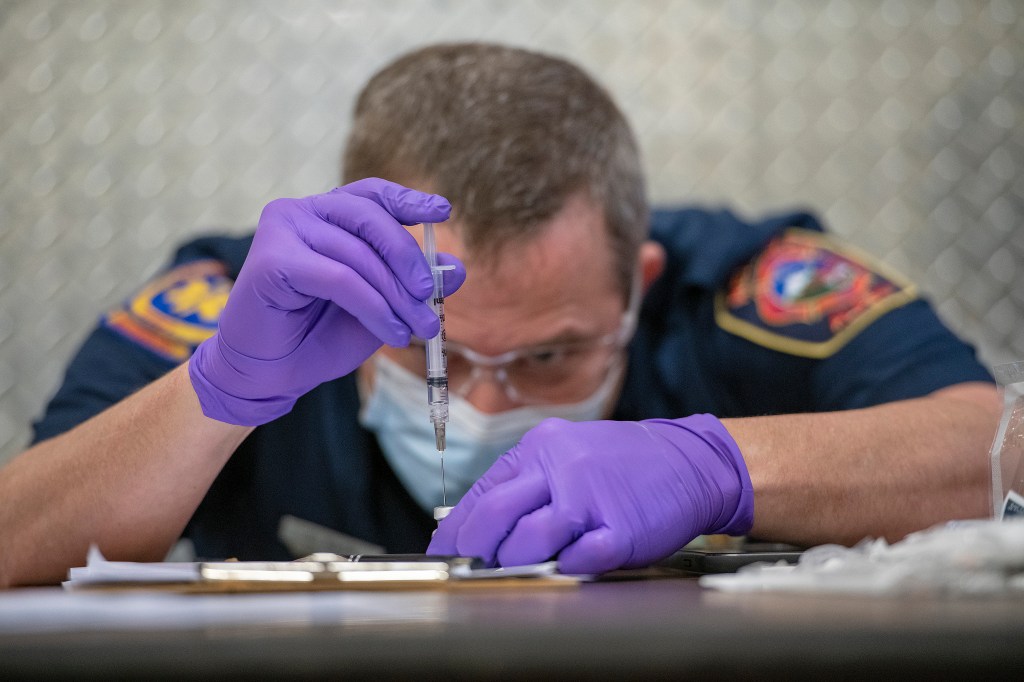 Greg Karlik, a senior paramedic, dilutes the Pfizer COVID-19 vaccine with 1.8ml of sodium chloride before agitating the mixture and then administering it as a shot to an EMS co-worker on Saturday, Dec. 19, 2020, at Fire Station 1 in Ketchikan, Alaska. (Du