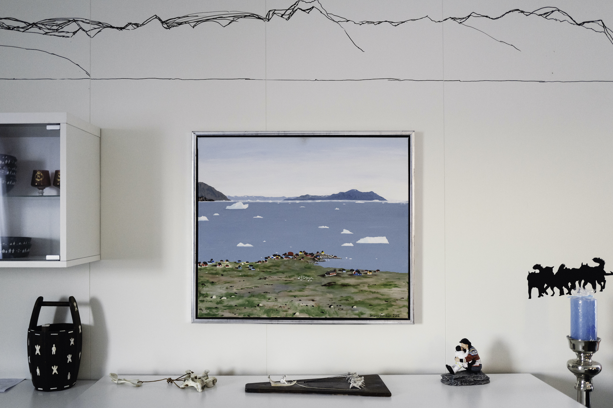 A painting of Nuugaatsiaq in the Møller family's new living room, a reminder of the home they've lost.