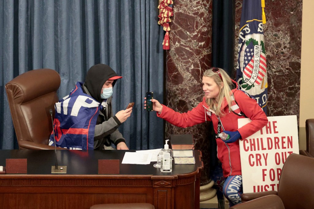 Christine Priola shows a cell phone to a man sitting in the vice president's chair on January 6, in Washington, D.C. (Getty Images)capitol-pence-chair-01