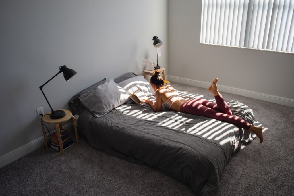 High Angle View Of Woman Reading Book While Lying On Bed At Home