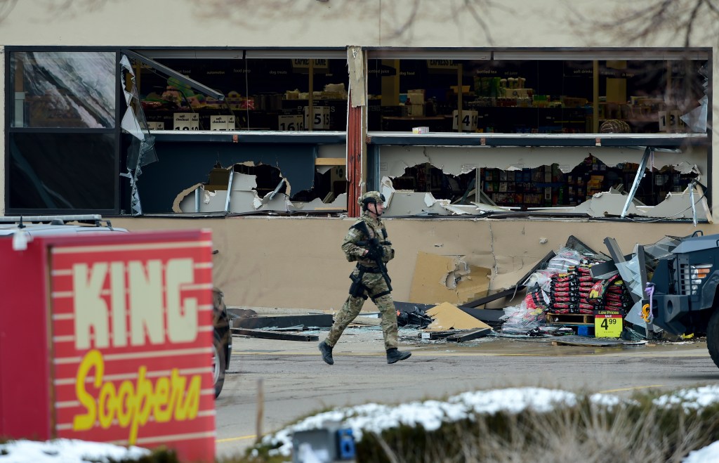 A police officer is seen outside broken windows at King Soopers on Table Mesa Drive in Boulder after reports of shots fired on Monday, March 22, 2021.