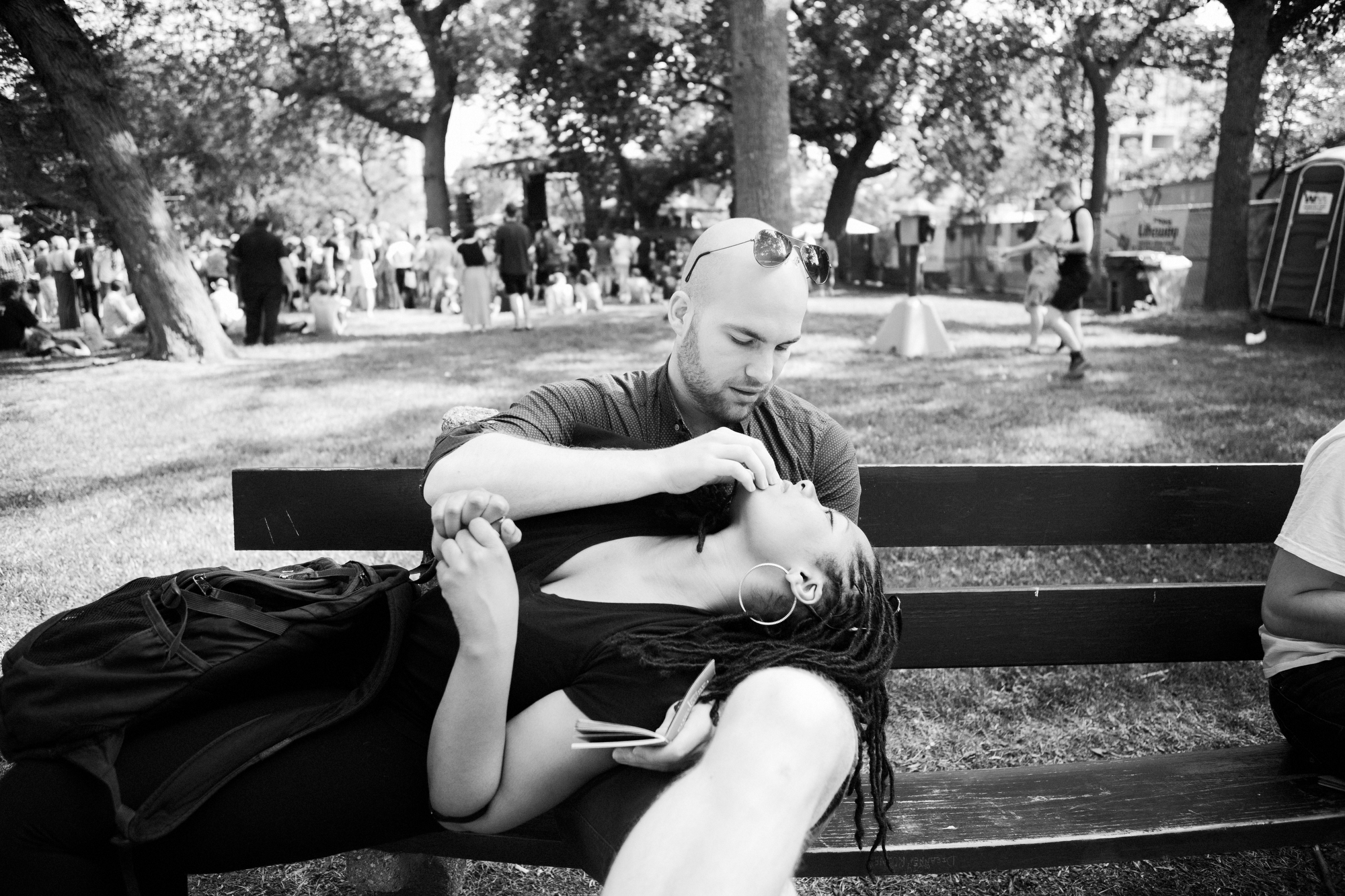 One person sitting on a bench while another person lays on top of them.