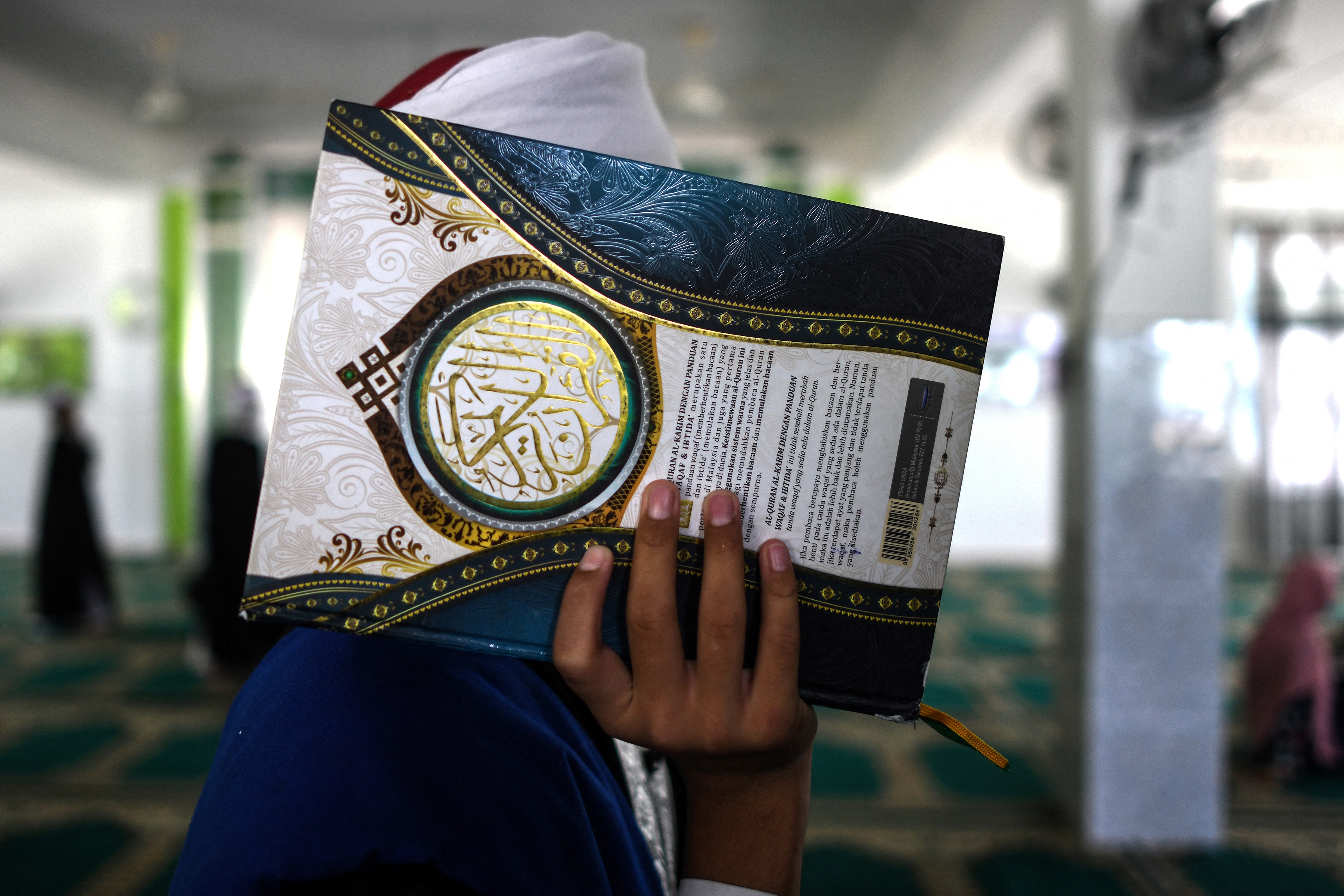 A Muslim man carries a copy of the Quran in a mosque in Bentong, Malaysia. PHOTO: AFP