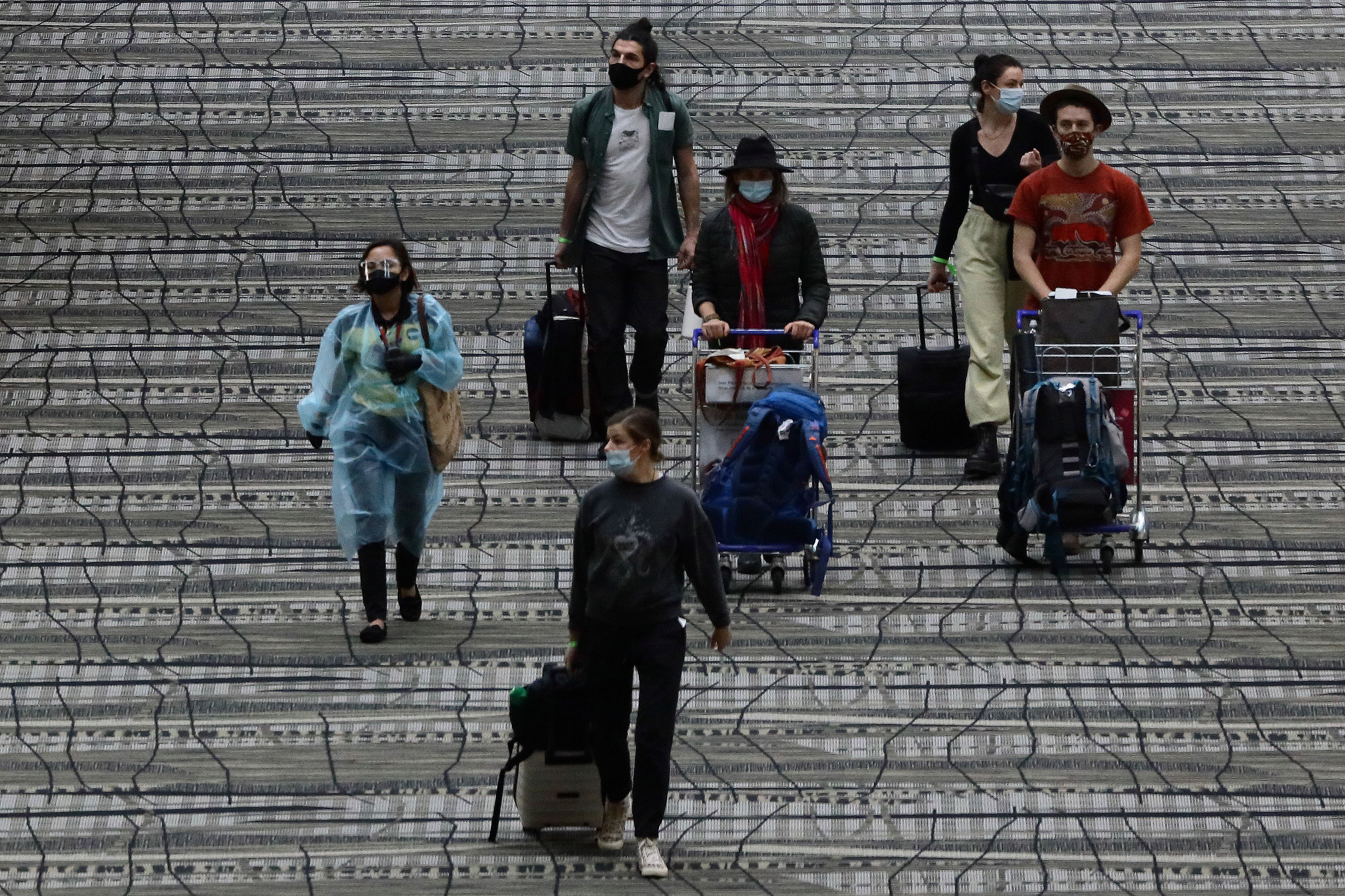 Travelers wearing protective mask walk along the transit area of Changi International Airport terminal