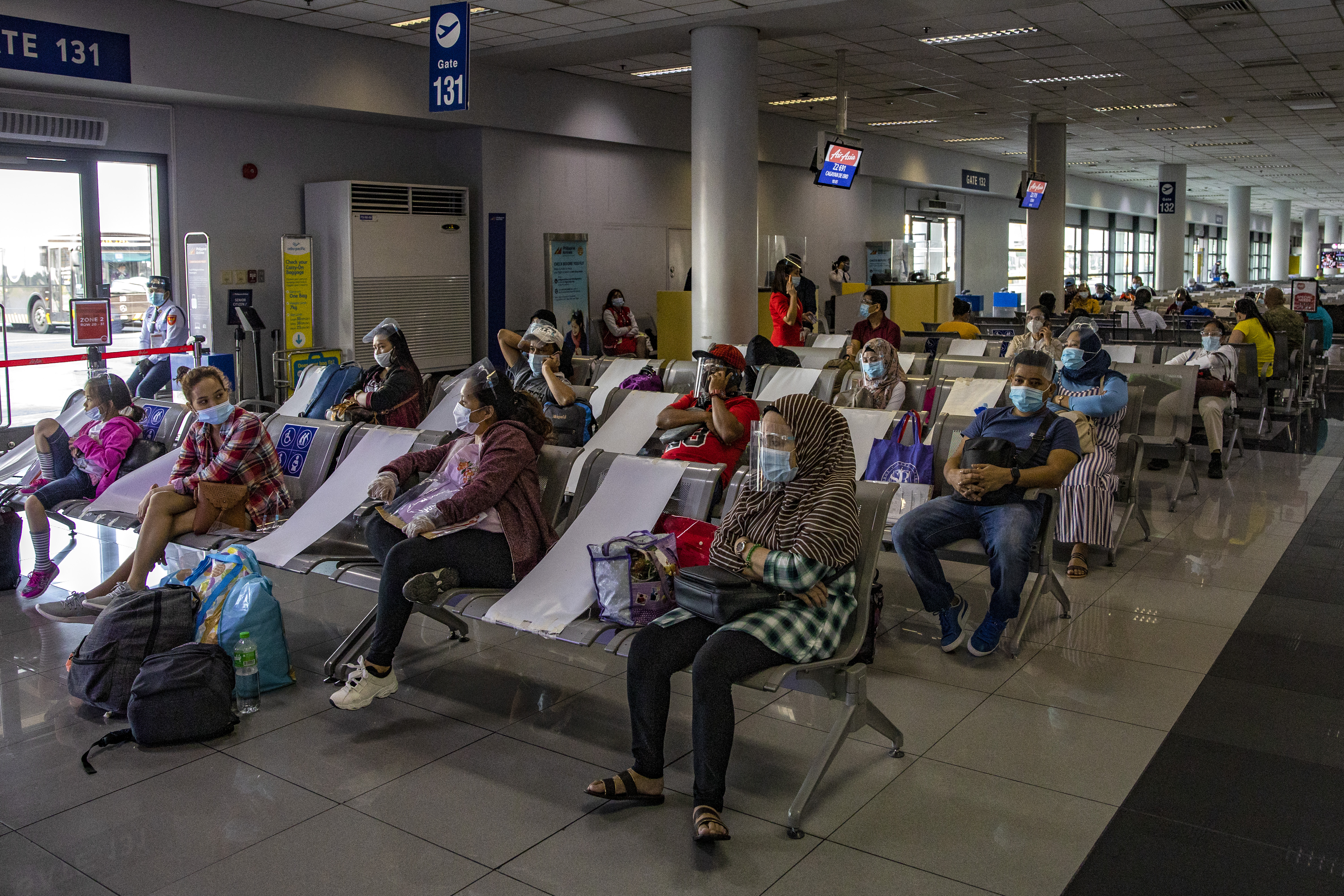 Travelers wearing face masks and face shields to protect against COVID-19 walk inside Ninoy Aquino International Airport