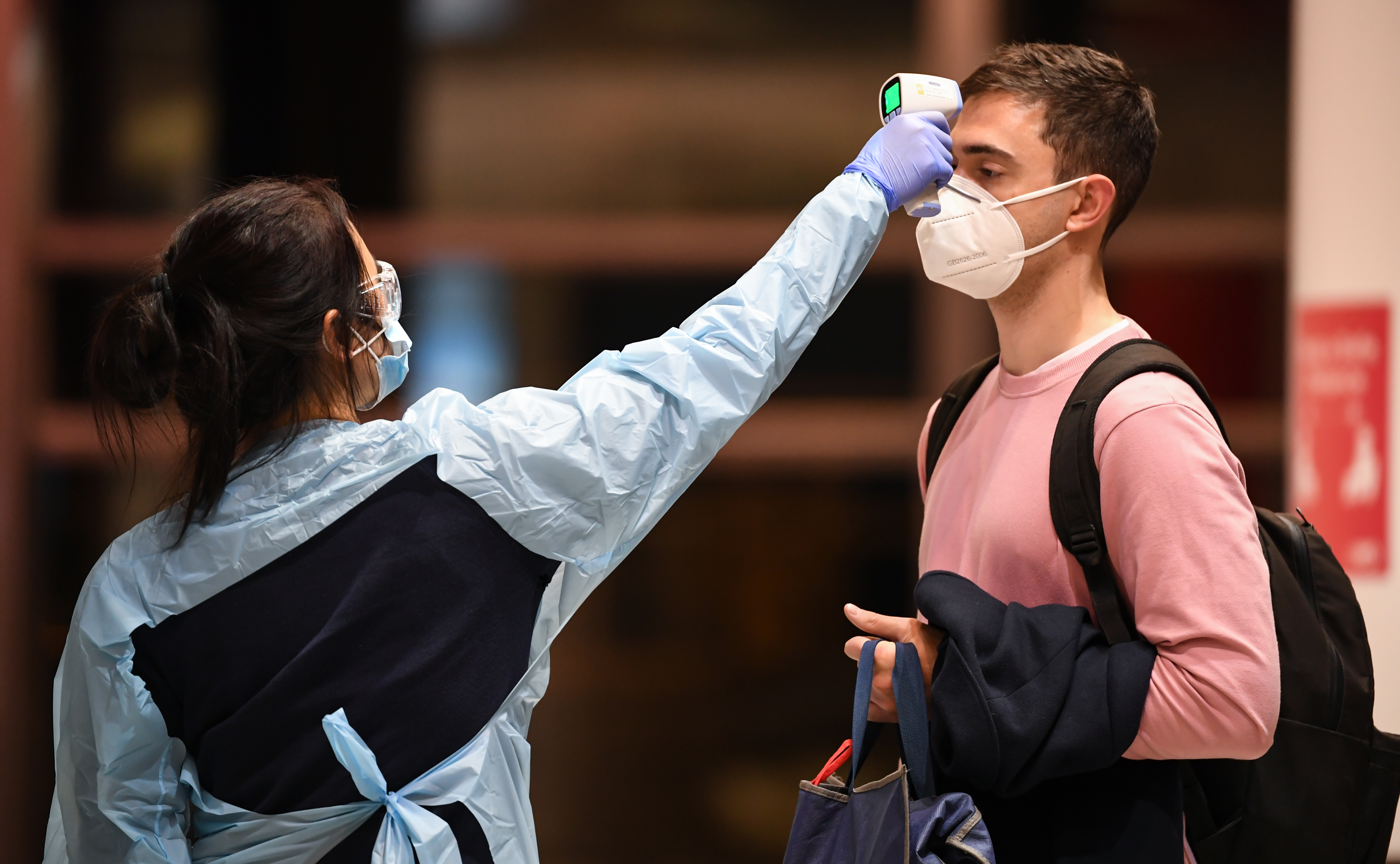 Passengers arrive from a Qantas flight that flew from Melbourne at Sydney Airport to be met by health officials taking their temperature