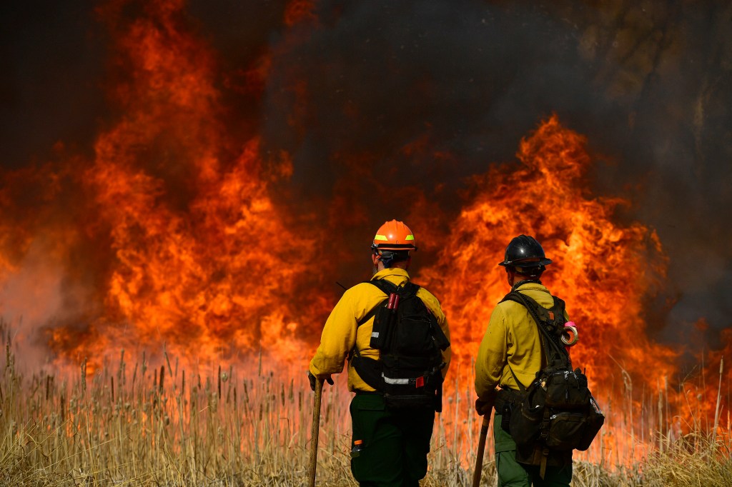 U.S. Fish and Wildfire firefighter Joe Murphy, left, and Denver firefighter Jordan Smith, right, keep an eye on the fire along the road during prescribed burn at the Rocky Mountain Arsenal National Wildlife Refuge on April 5, 2021 in Denver, Colorado.(Hel