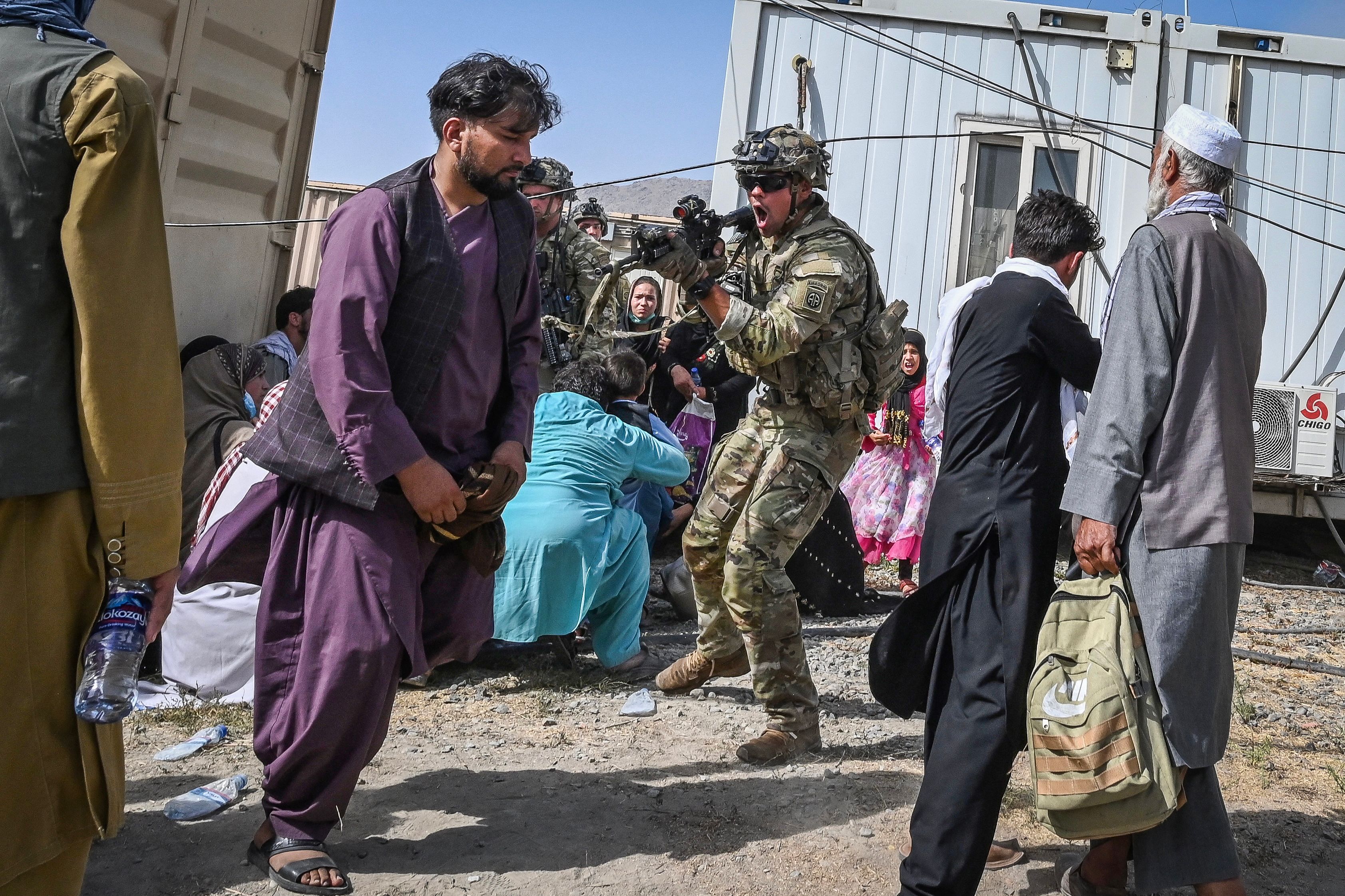 A US soldier (C) point his gun towards an Afghan passenger at the Kabul airport in Kabul on August 16, 2021, after a stunningly swift end to Afghanistan's 20-year war, as thousands of people mobbed the city's airport trying to flee the group's feared hardline brand of Islamist rule. (Photo by Wakil KOHSAR / AFP) (Photo by WAKIL KOHSAR/AFP via Getty Images)