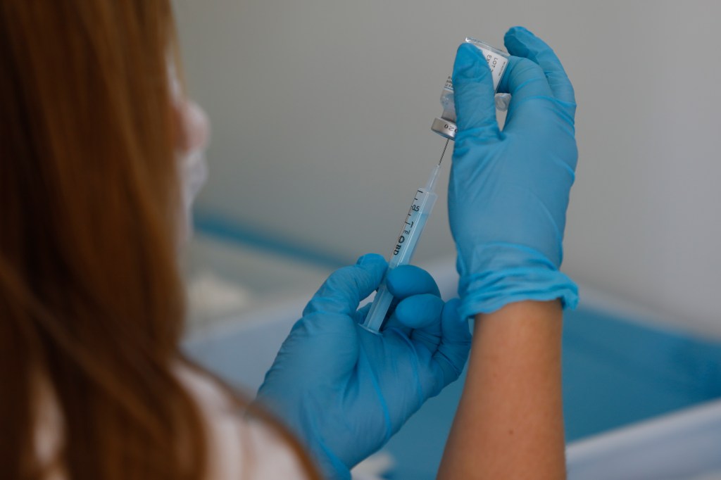 A person puts a COVID vaccine in a syringe.