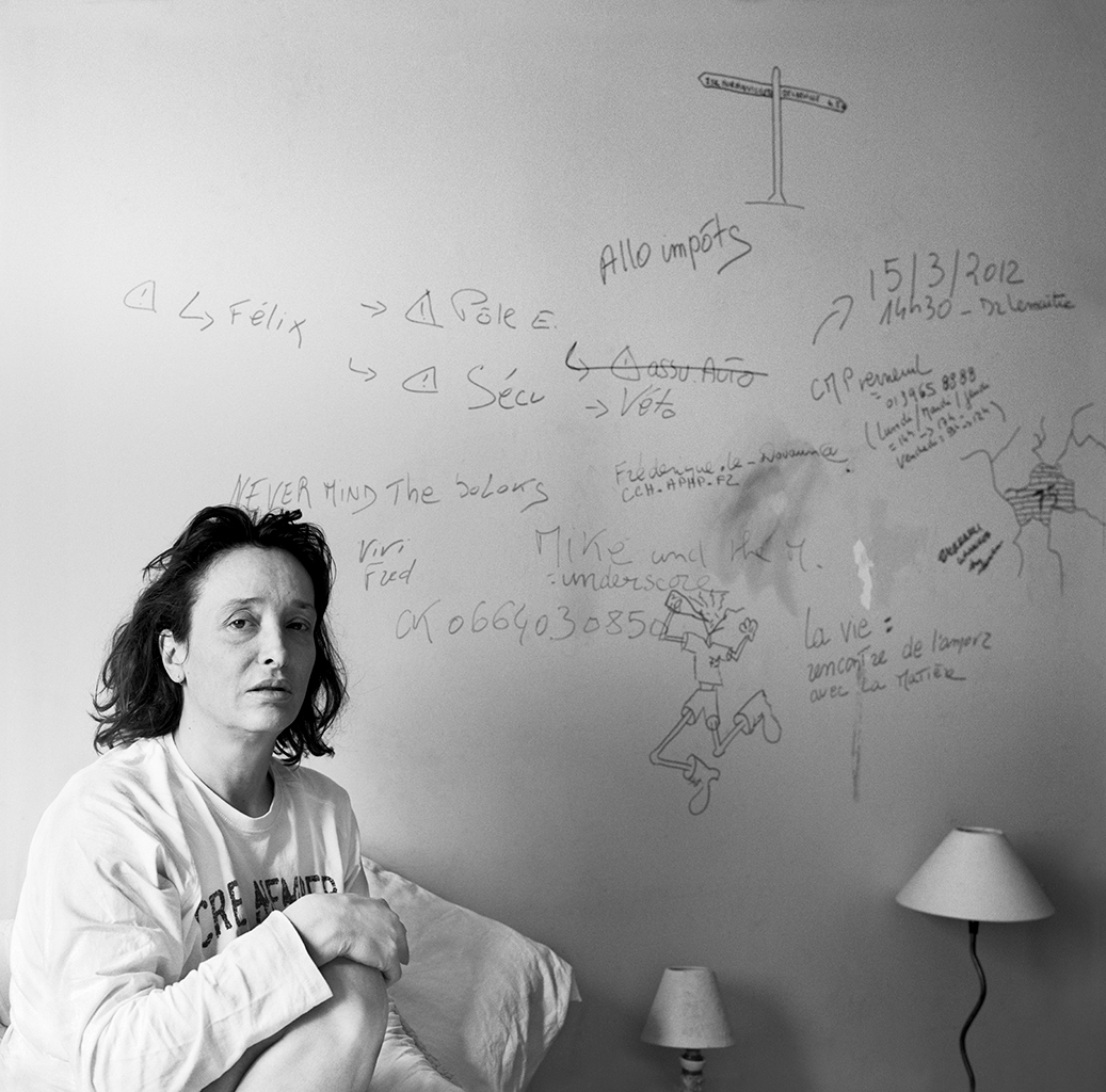 Mathias de Lattre, France, magic mushrooms - Black and white photo of a woman sat in front of a scrawled-upon wall.