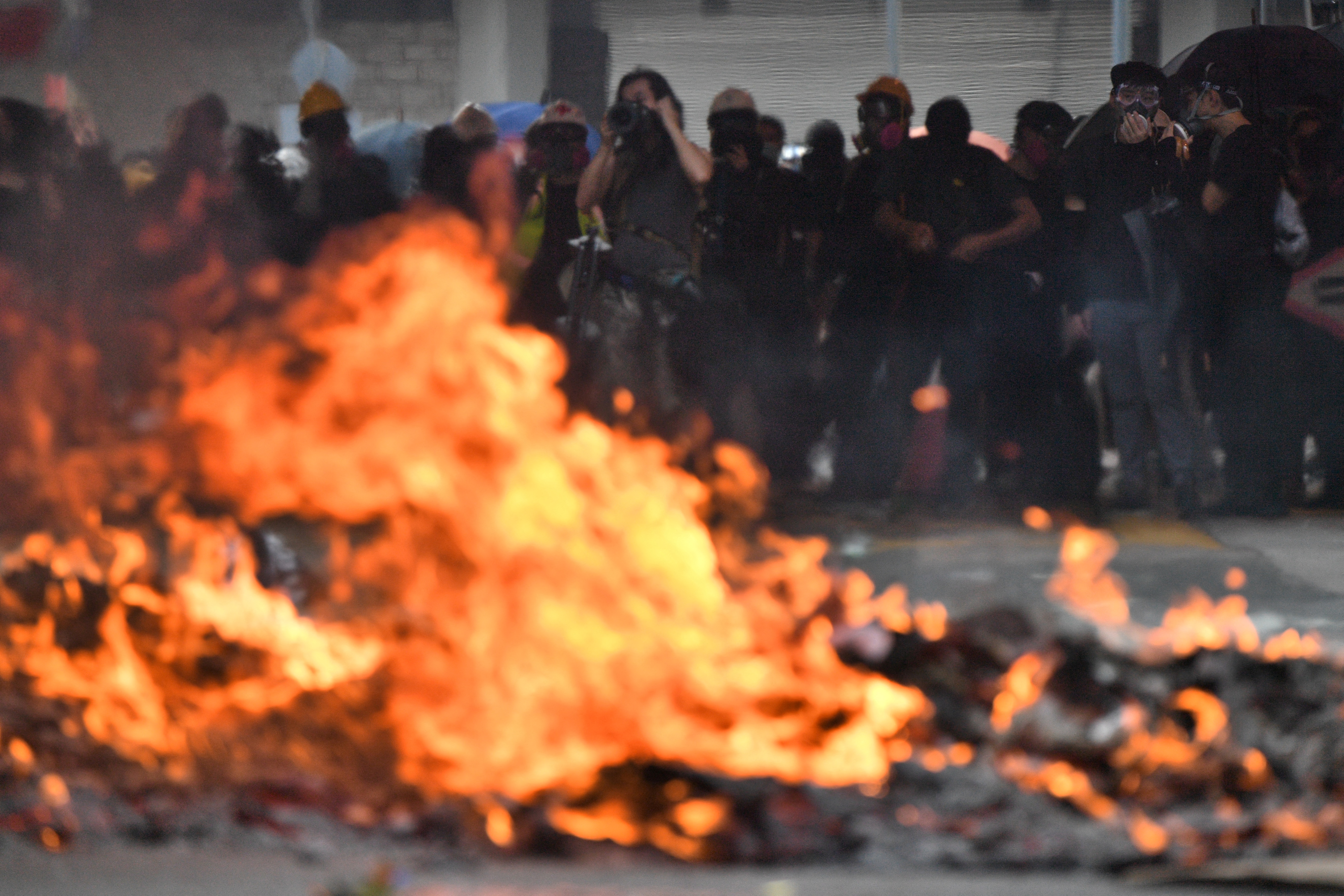 Protesters look on as a barricade burns during demonstrations through the streets of Hong Kong on the 70th anniversary of the founding of the People’s Republic of China in 2019. Photo: Anthony WALLACE / AFP