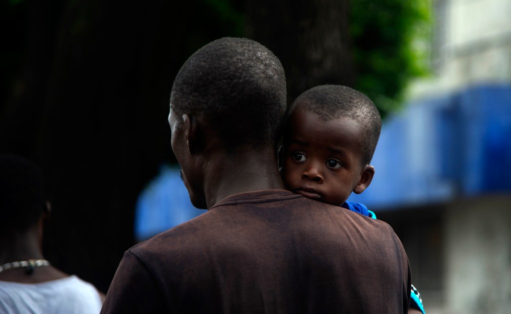 A Haitian migrant holding a child marches to the Siglo XXI Migratory Station in Tapachula, Chiapas, Mexico, on September 15, 2021.