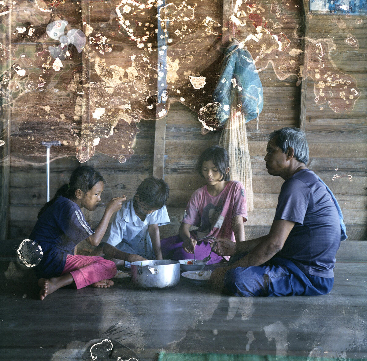 MengHy having lunch with his siblings and grandfather in their floating house. Image: Lim Sokchanlina / Save the Children