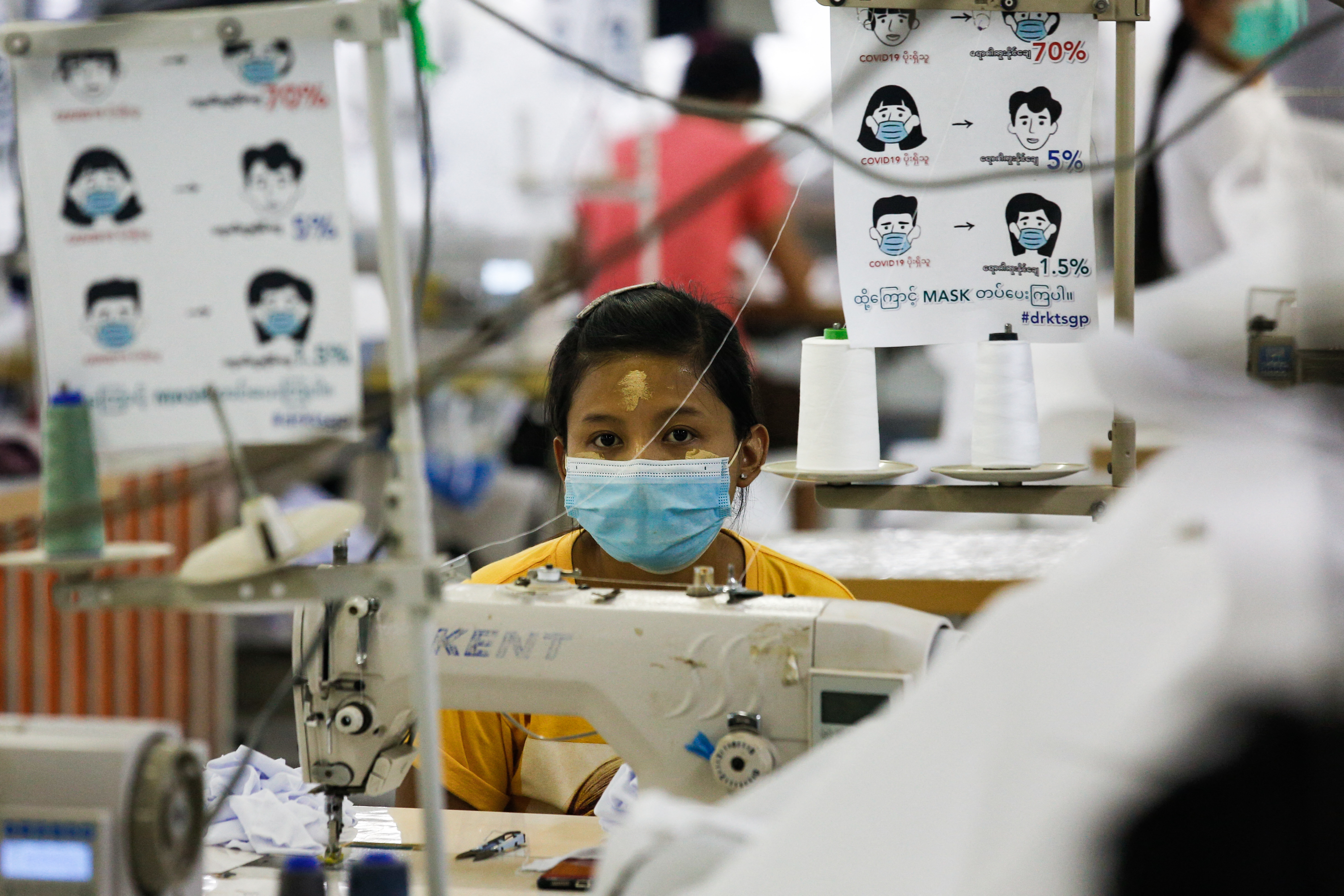 A worker wearing a face mask sews disposable surgical gowns for health workers as protection from the COVID-19 coronavirus at a garment factory in Yangon on May 8, 2020. Photo: Sai Aung Main / AFP