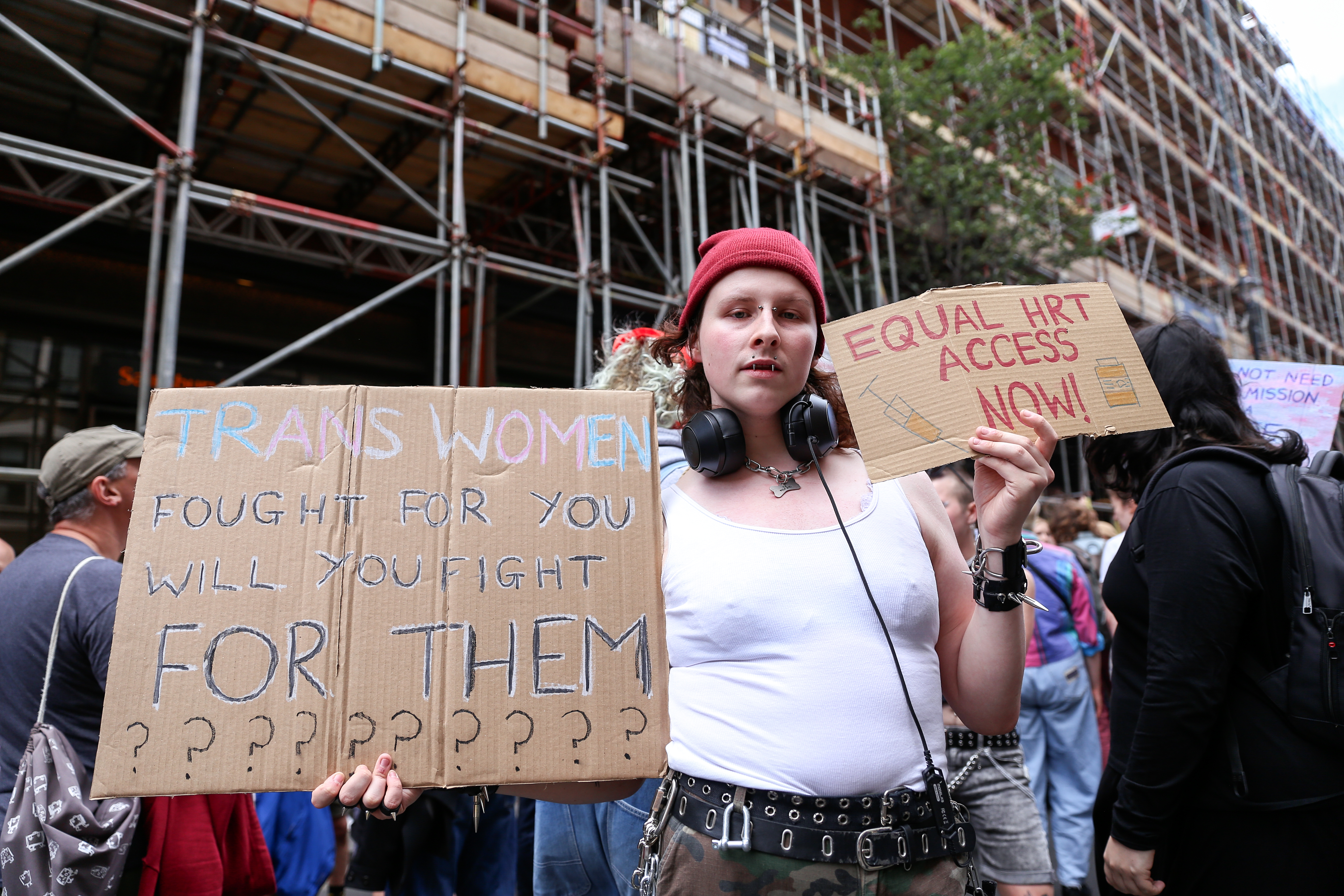 Gay Liberation Front protester holding up signs demanding trans equality and hormone treatment