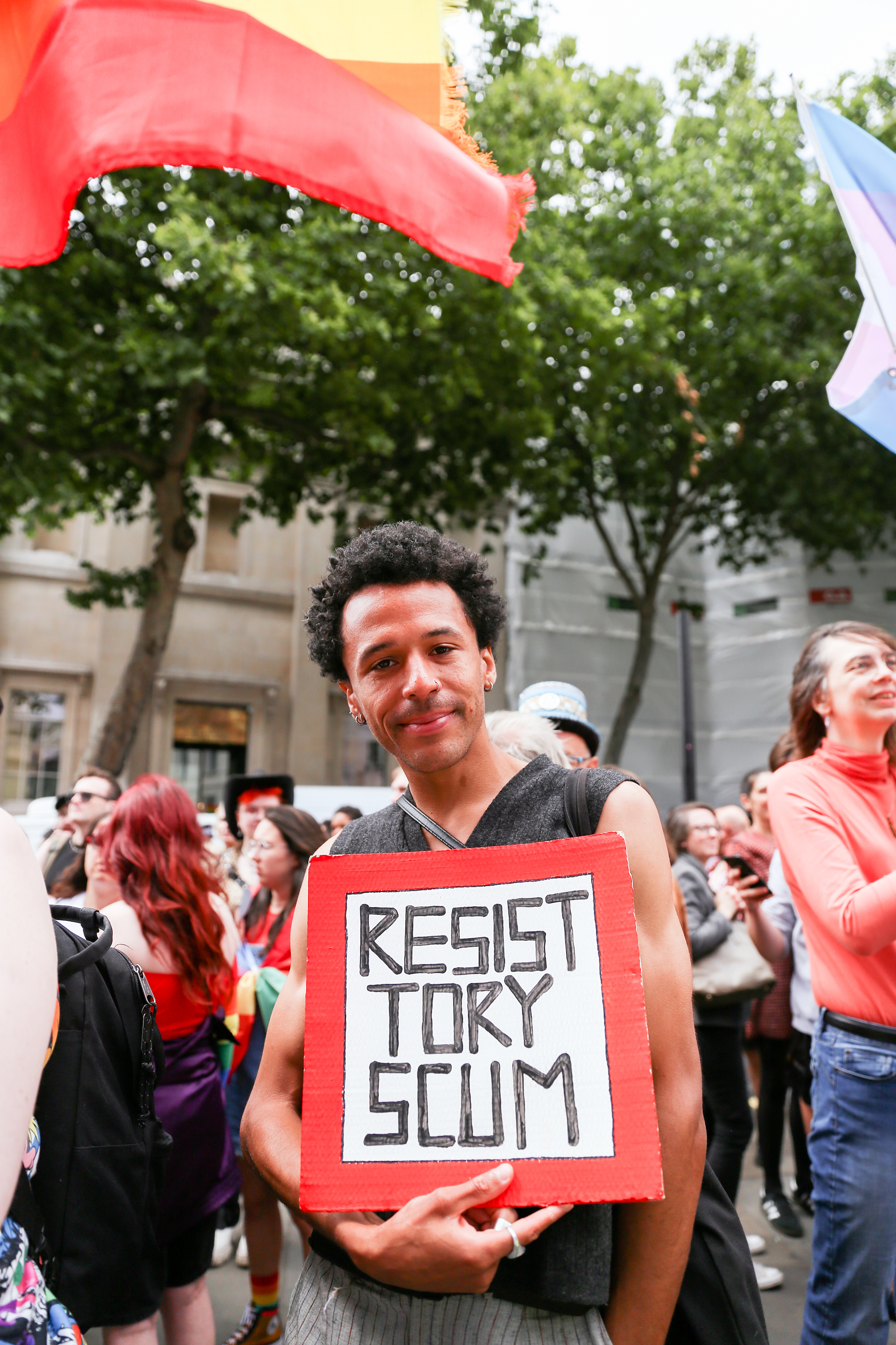 Gay Liberation Front march attendee holding up sign saying Resist Tory Scum