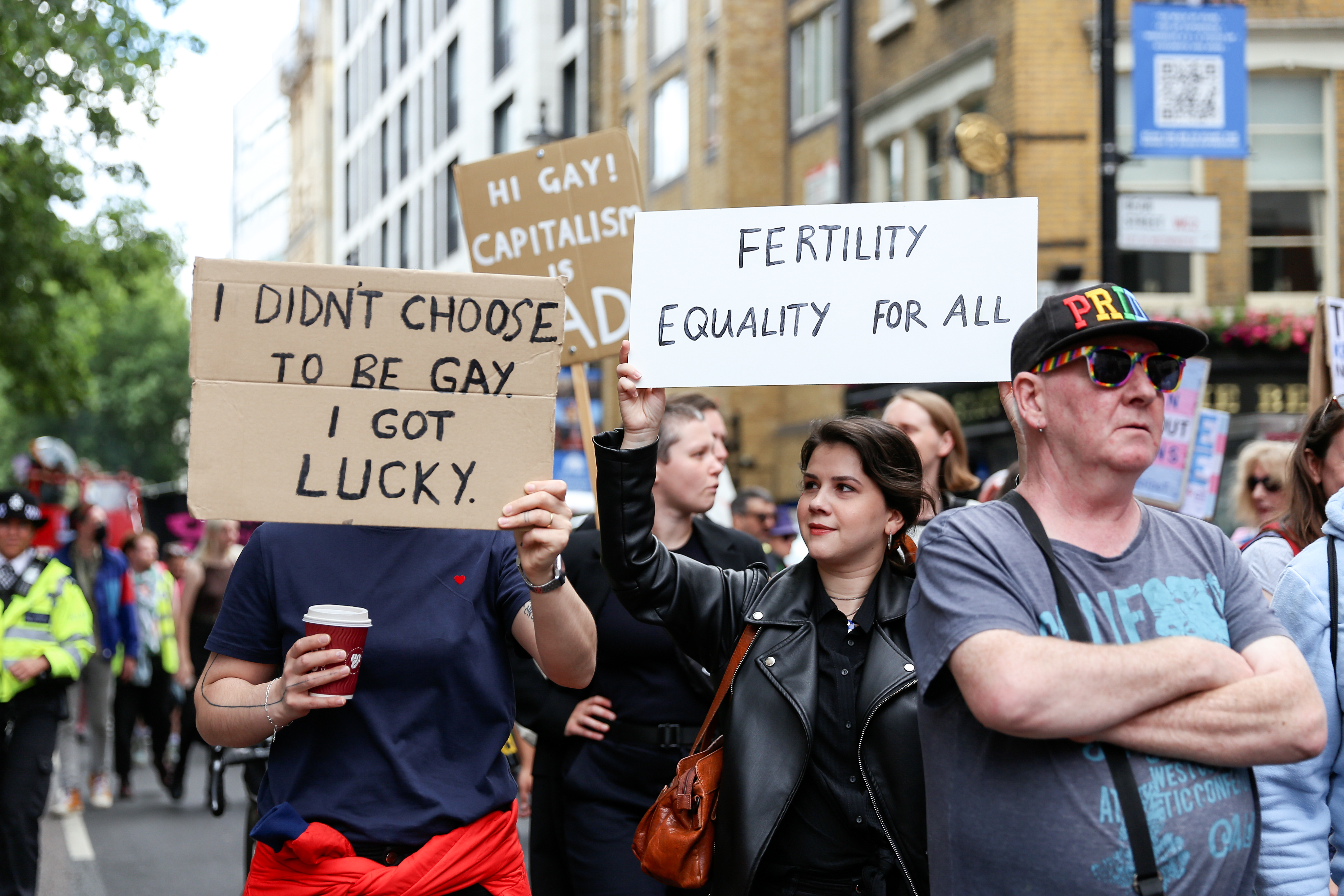 Gay Liberation Front marchers holding signs reading 'I didn't choose to be gay, I got lucky' and 'fertility equality for all'