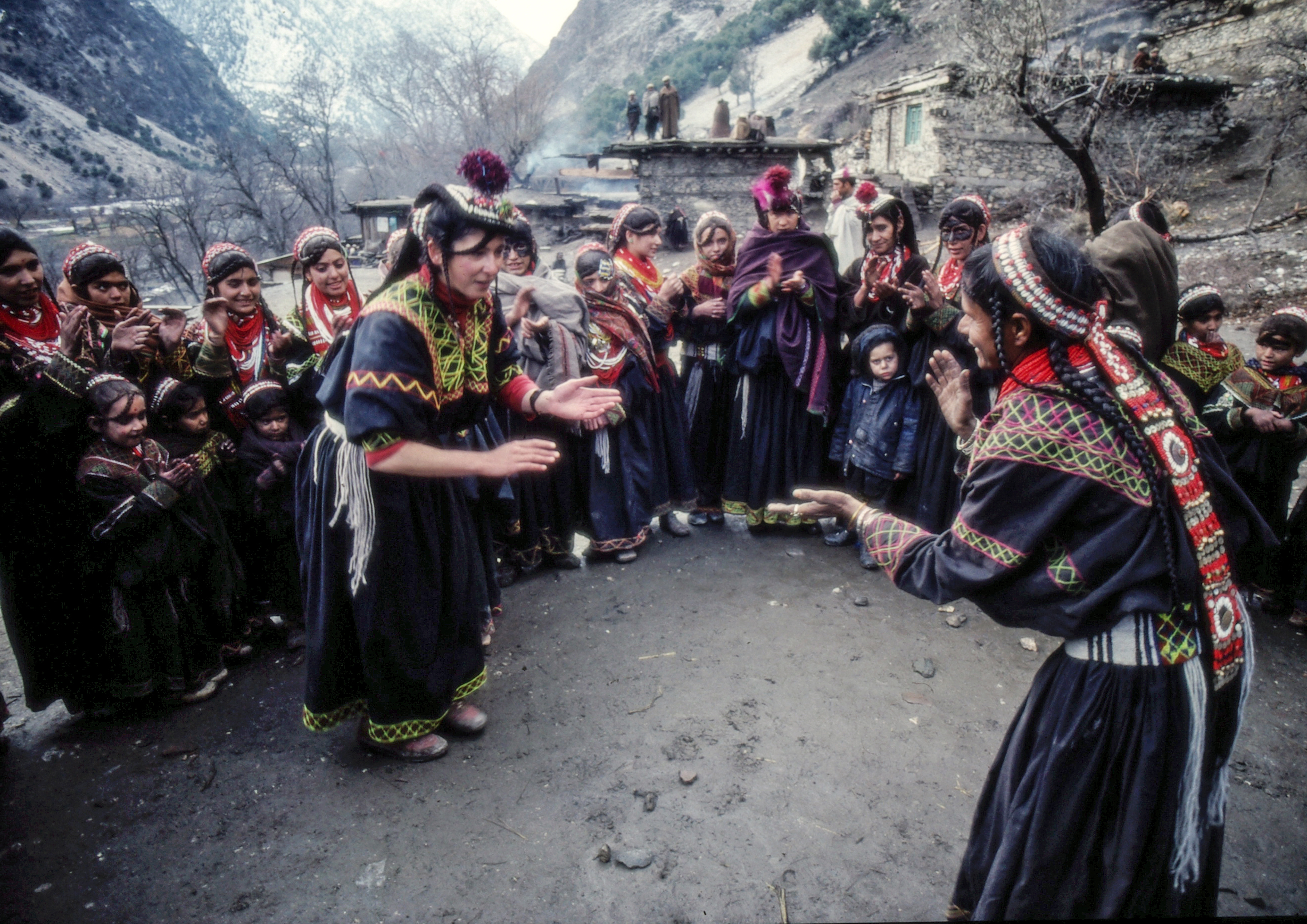 Italo Bertolasi, Italian Hippies – photos of a circle of women wearing traditional garments with colourful embroideries standing in the middle of a circle surrounded by people.