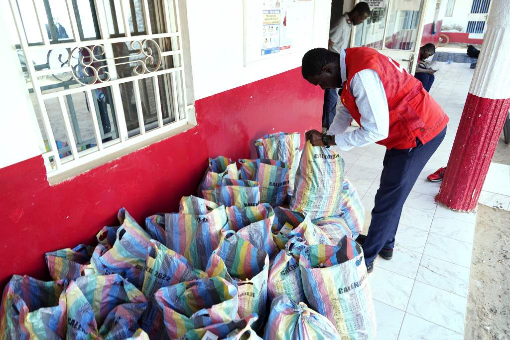 A member of the Gambian Red Cross looks through sacks of collected cough syrups in Banjul