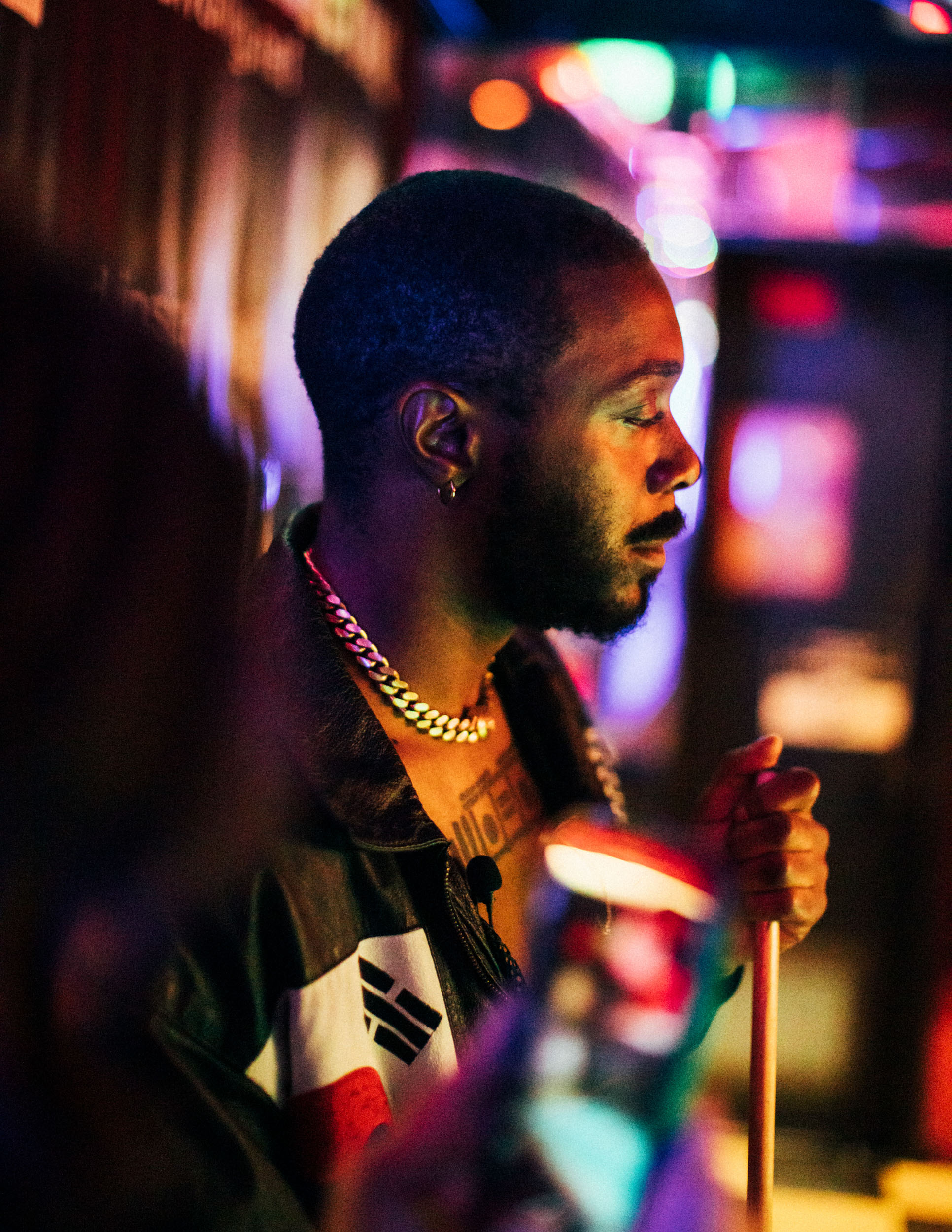 JPEGMAFIA holding a pool stick in a neon lit bar